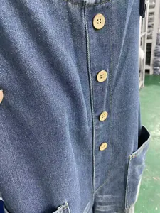 Close-up of distressed blue denim overalls with rustic wooden buttons and pocket detail.