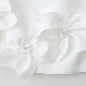 Elegant white crop top featuring 3D fabric flower decorations and smooth woven texture