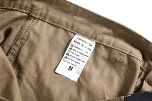 Detail of care label on men's 100% cotton cargo pants showing washing instructions