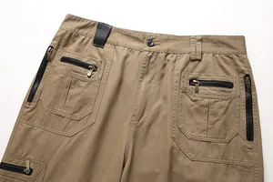 Detail view of khaki men's cargo pants showing multiple functional zipper pockets.