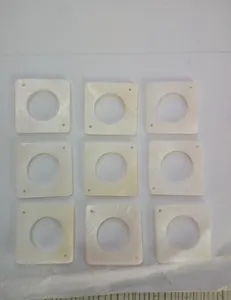 Close-up detail of nine 25mm square mother of pearl shell pieces for DIY jewelry