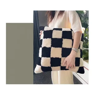 Modern black and white checkerboard faux rabbit fur pillow cover held by model