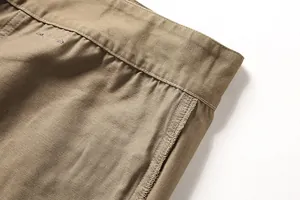 Close-up of durable stitching on khaki cotton cargo pants, showing fabric texture.
