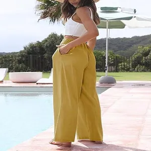 Femme portant un pantalon large en coton et lin jaune décontracté au bord d'une piscine