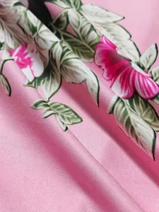 Gros plan d'un tissu de robe à fleurs roses avec texture sergée et imprimé hibiscus