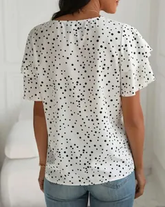 Vista posteriore di una maglia bianca a pois con maniche a principessa con volant.