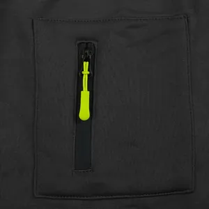 Primo piano della tasca con cerniera e tirante verde neon su una tuta cargo pesante da uomo