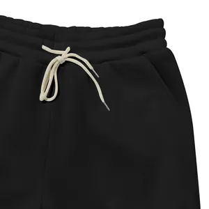 Dettaglio dei pantaloni sportivi in pile nero con vita elastica e coulisse color crema