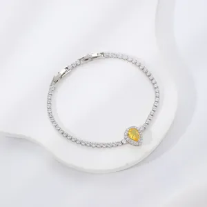 Dettaglio di bracciale tennis argento con una pietra preziosa gialla a goccia al centro