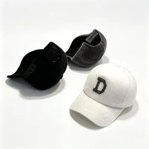 Close-up of fuzzy mink fur baseball caps in black, grey, and white with rhinestone D