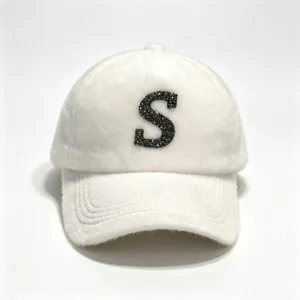 Close-up of a fluffy white faux mink fur baseball cap with a glittery black letter S.