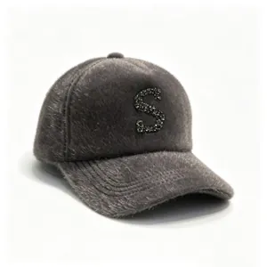 Close-up of a grey faux mink fur baseball cap featuring a sparkly rhinestone letter S.