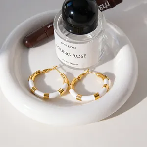 Vue détaillée de créoles en acier inoxydable plaqué or 18 carats sur plat blanc