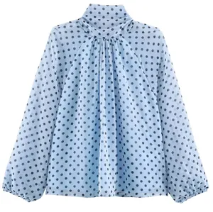 Gedetailleerd vooraanzicht van lichtblauwe blouse met zwarte stippen en pofmouwen