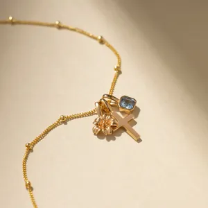 Elegant gold stainless steel necklace with flower, cross, and blue gemstone charms