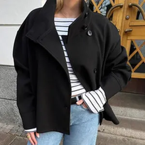 Detail shot of a loose black jacket with stand collar worn over a striped shirt.