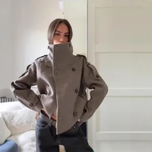 Woman wearing a stylish high-collar taupe wool jacket in a minimalist indoor setting