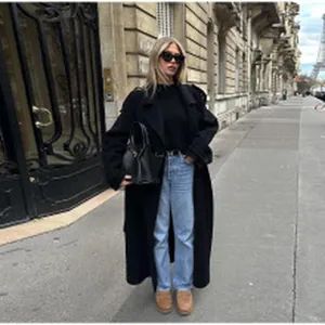 Chic street style view featuring a long black coat and blue wide-leg jeans in Paris city