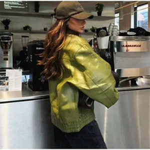 Detailed back view of a stylish glossy green faux leather jacket in a modern cafe setting