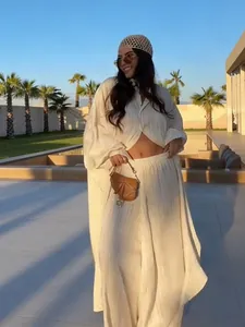 Elegant white pleated two-piece set with long shirt and wide-leg trousers outdoors