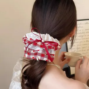 Achteraanzicht van een rode gingham scrunchie met kant en strik op bruin haar.