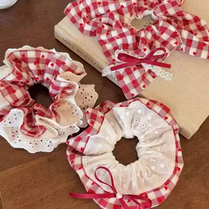 Detail van rode ruitjes scrunchies met hartjespatroon, kant en een strikdetail.