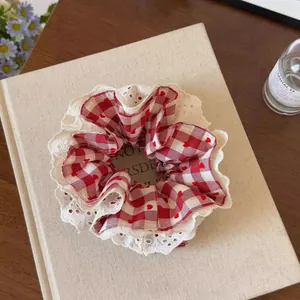 Detail van een rode ruitjes haarelastiek met hartjes en een witte kanten rand.