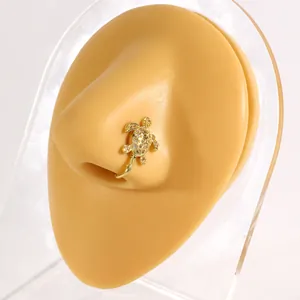 Golden turtle non-piercing nose clip with zircon stones displayed on a nose model.