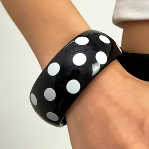Detailansicht eines breiten schwarzen Harzarmreifens mit weißem Polka-Dot-Muster