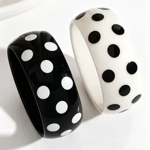 Detailansicht von stilvollen schwarz-weißen Harzarmreifen mit Polka-Dot-Muster und Glanz
