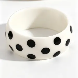 Detailaufnahme eines weißen Harz-Armreifs mit klassischen schwarzen Polka-Dots