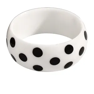 Detailansicht eines klobigen weißen Harzarmbands mit klassischem schwarzem Polka-Dot-Muster