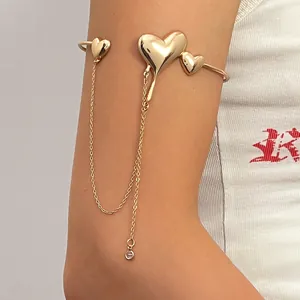 Detailed view of a golden lava heart arm cuff with long dangling chain tassels on arm
