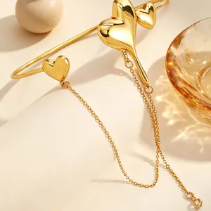 Detailed view of gold molten heart armlet with long dangling chains and crystal charm.