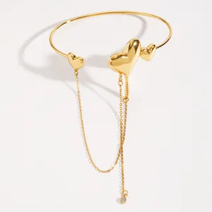 Detailed view of a golden lava heart arm cuff featuring a long chain tassel and polished finish