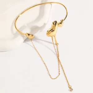 Detailed view of the elegant gold molten heart arm cuff featuring a long dangling chain tassel.