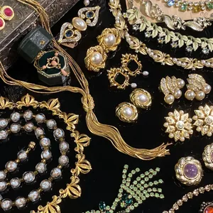 Gedetailleerde macro-weergave van vintage gouden sieradencollectie met parels en emaille.