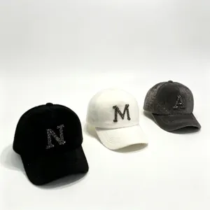 Close-up of three warm plush baseball caps with rhinestone letters A, N, and M.