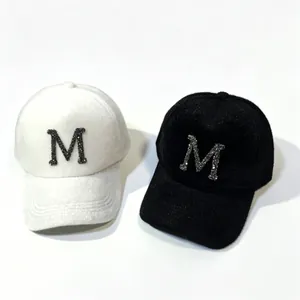 Close-up of white and black winter baseball caps with rhinestone M and soft plush texture