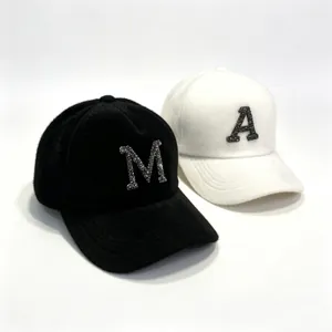 Detailed view of black and white mink fur baseball caps with sparkly rhinestone letters