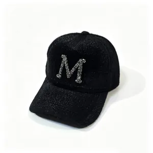 Detailed macro view of a black faux mink fur baseball cap with rhinestone letter M