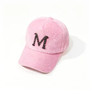 Detail shot of a cozy pink faux mink fur baseball cap featuring a rhinestone letter M