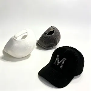 Detailed view of three warm faux mink fur baseball caps with rhinestone M letter