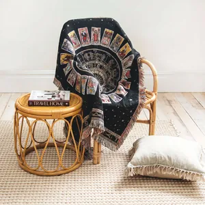 Detail shot of bohemian tarot zodiac woven blanket draped on rattan chair in cozy room.