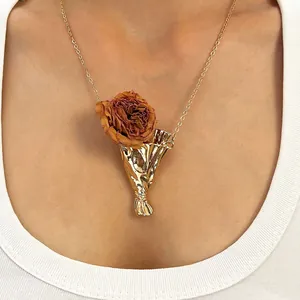 Elegante collar de jarrón dorado con una rosa seca real para un estilo artístico