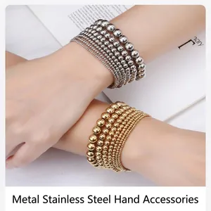 Detailed view of layered gold and silver stainless steel bead bracelets on wrist