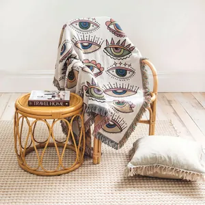 Couverture tissée bohème avec motif d'oeil mystique sur une chaise en rotin