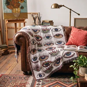 Couverture tissée bohème aux motifs d'yeux colorés sur un canapé en cuir vintage