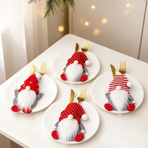 Nahaufnahme von vier festlichen Weihnachts-Gnom-Besteckhaltern auf weißen Tellern mit Besteck
