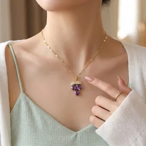 Elegant gold grape pendant necklace featuring purple zircons and diamond leaves worn by a model.